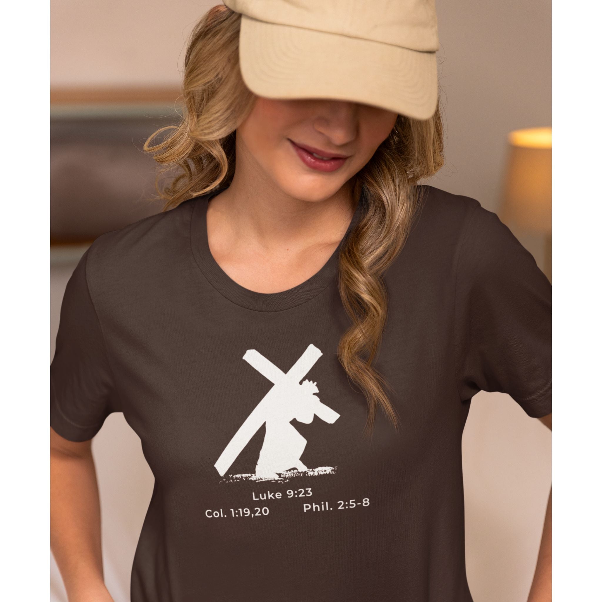 Woman wearing a brown t-shirt with a white graphic and text, indoors.
