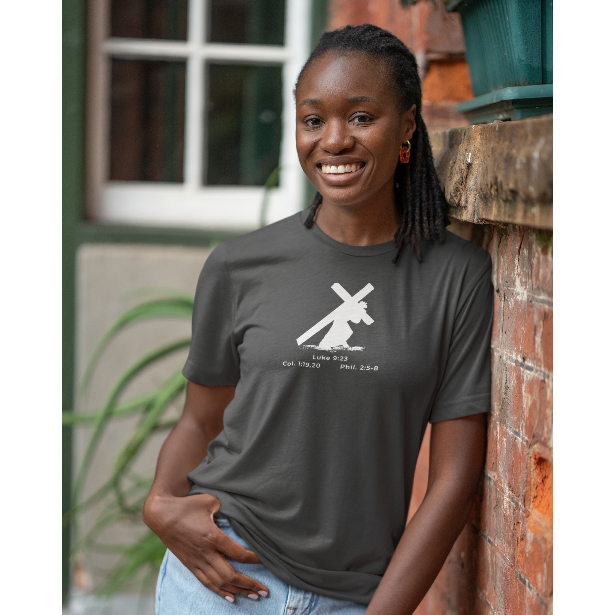 Woman wearing a dark gray t-shirt with a graphic design, standing against a brick wall.