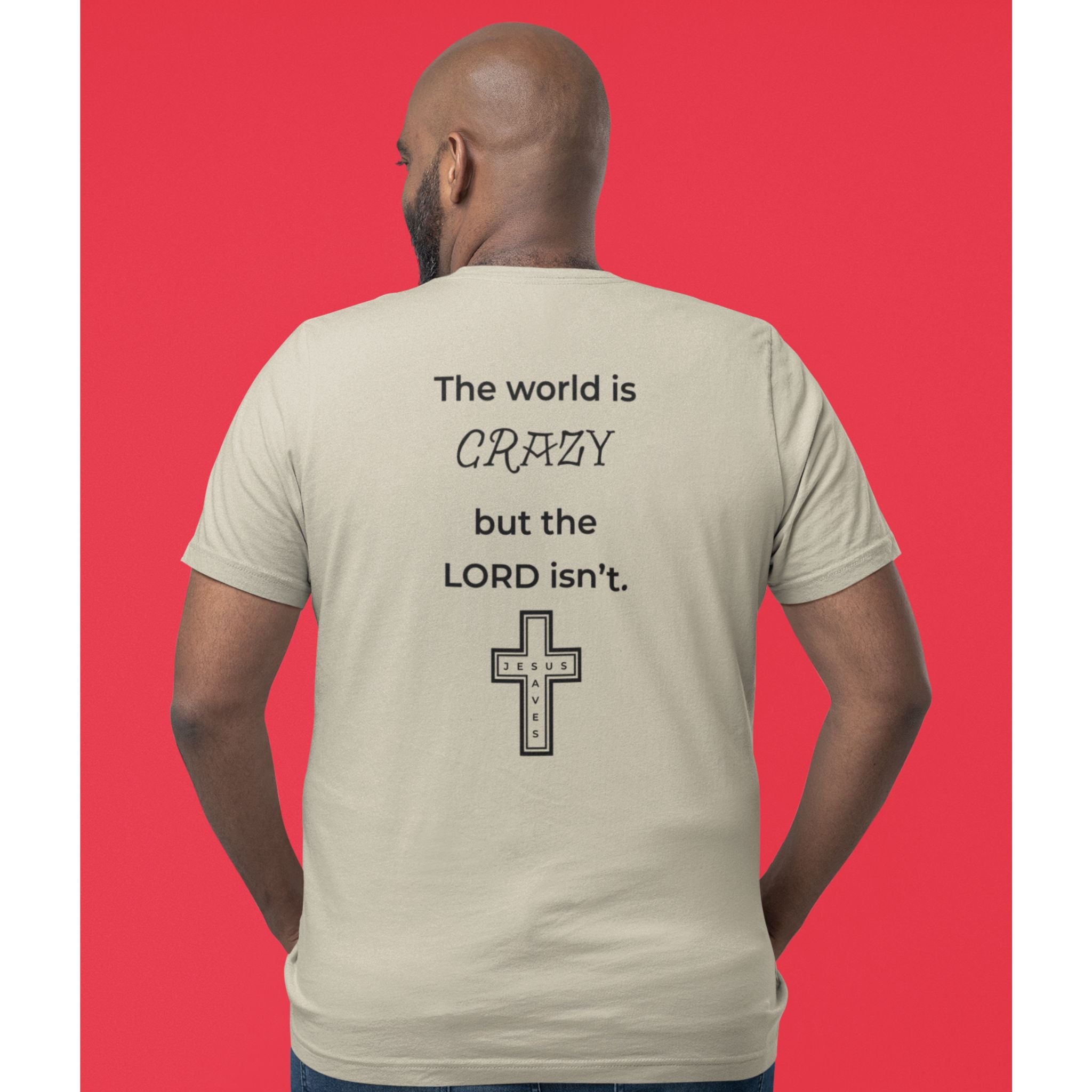 Back view of a sand-colored t-shirt with a black text design reading “The world is crazy but the Lord isn’t” and a small Jesus Saves cross detail.