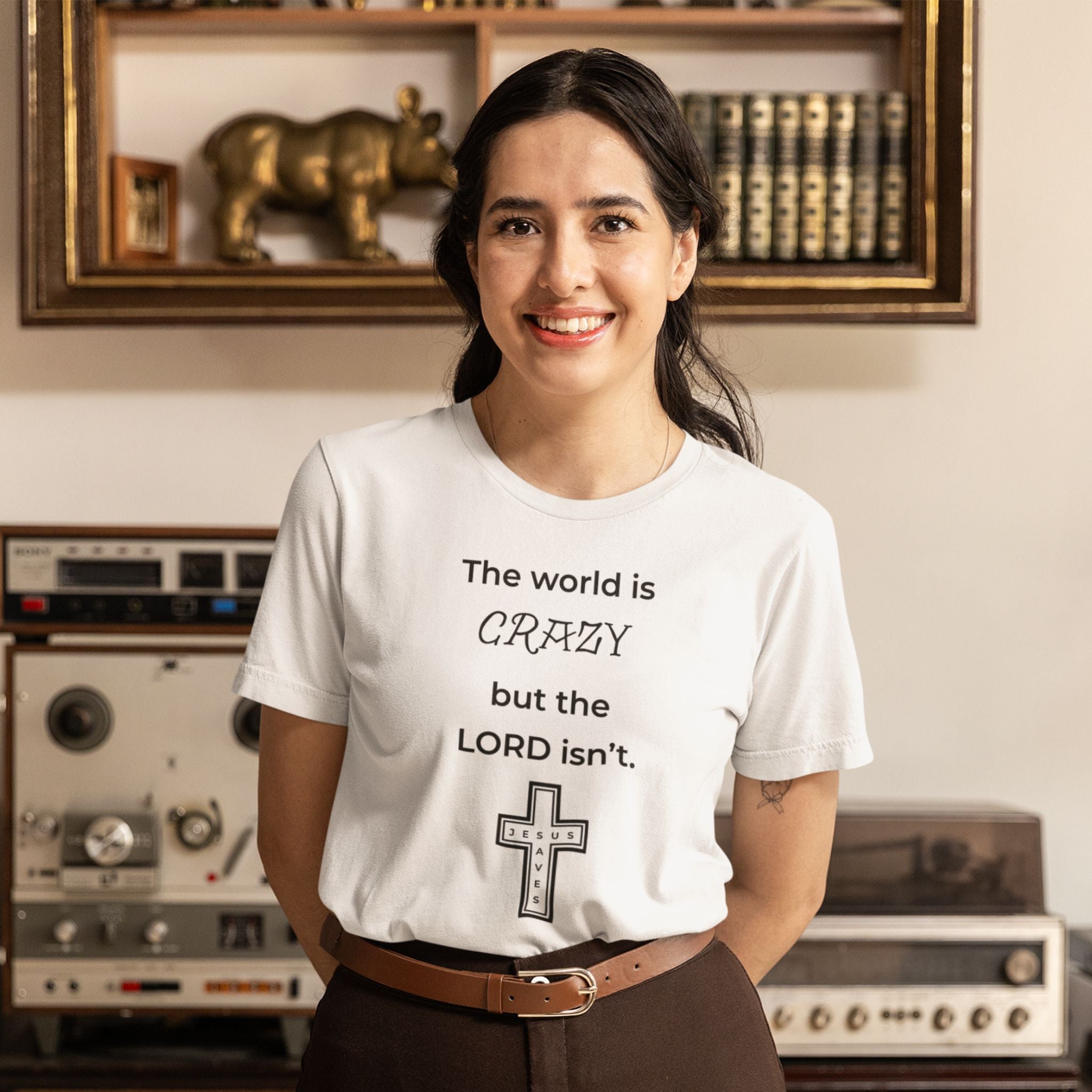 Woman wearing a light gray t-shirt with a black text design, standing in a room with vintage equipment and decor.