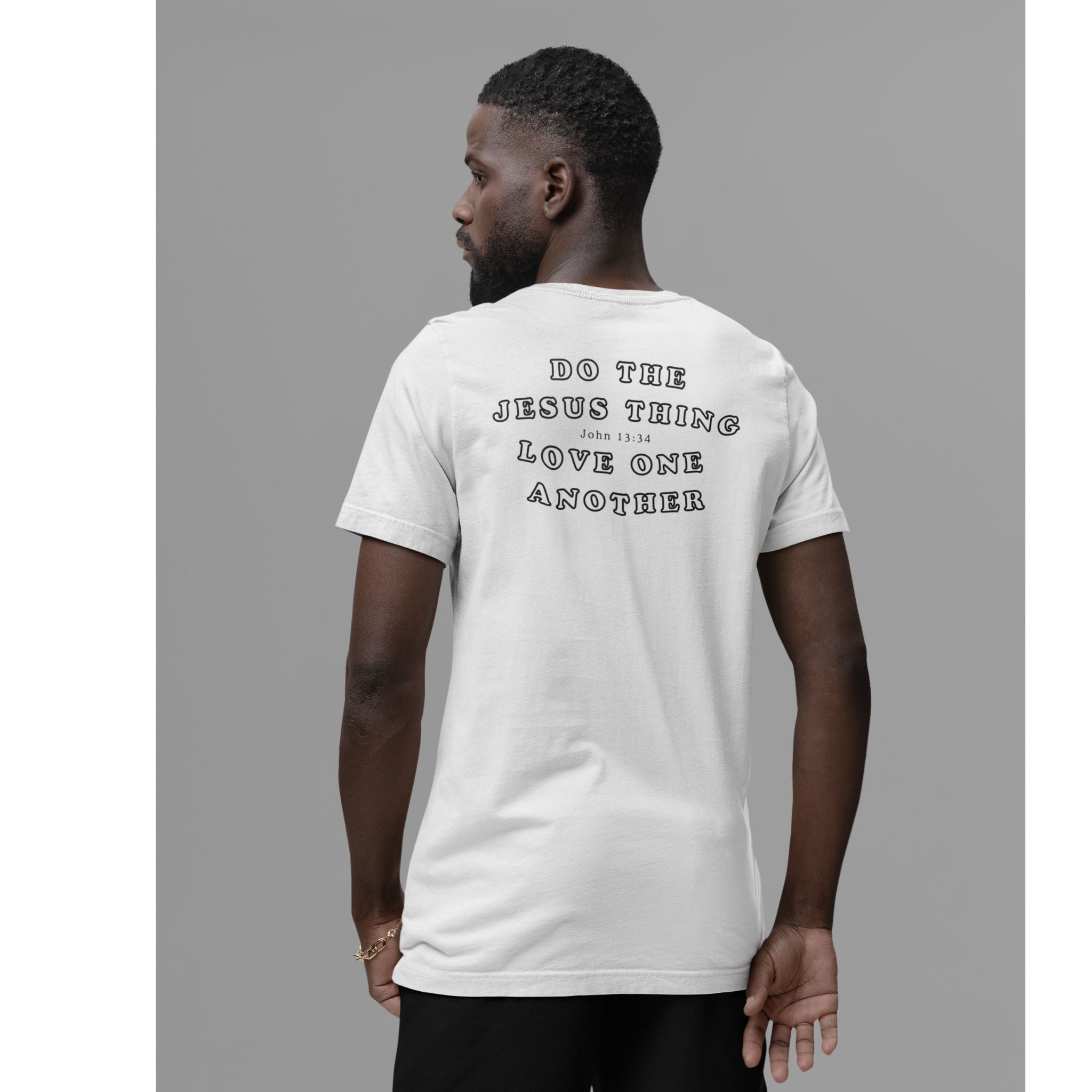 A man viewed from the back wearing an ash gray t-shirt with black text that reads 'DO THE JESUS THING LOVE ONE ANOTHER' on a solid gray background.