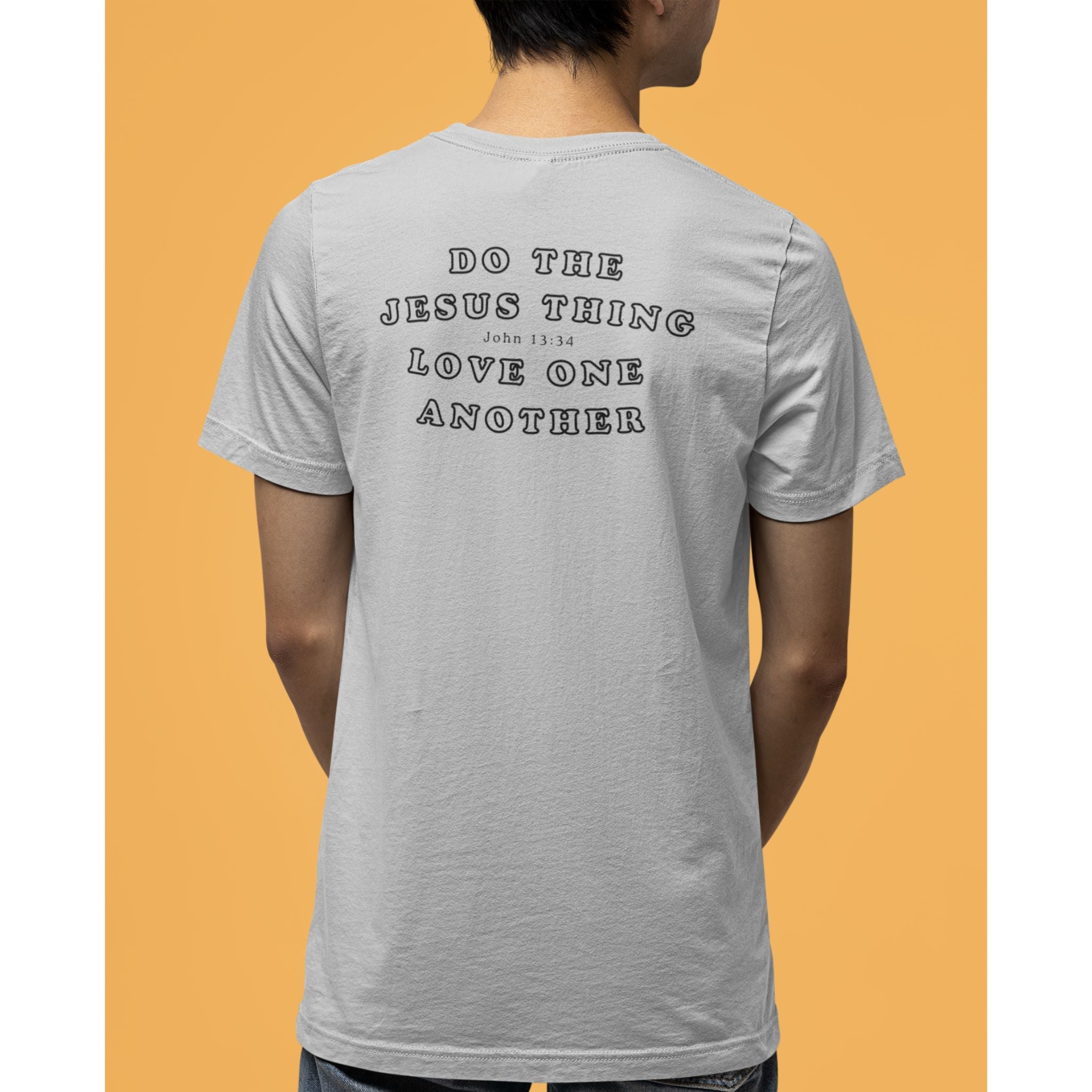 A man wearing a light gray t-shirt from the back, featuring the text 'DO THE JESUS THING LOVE ONE ANOTHER' in a black outline font. The background is a solid orange color.