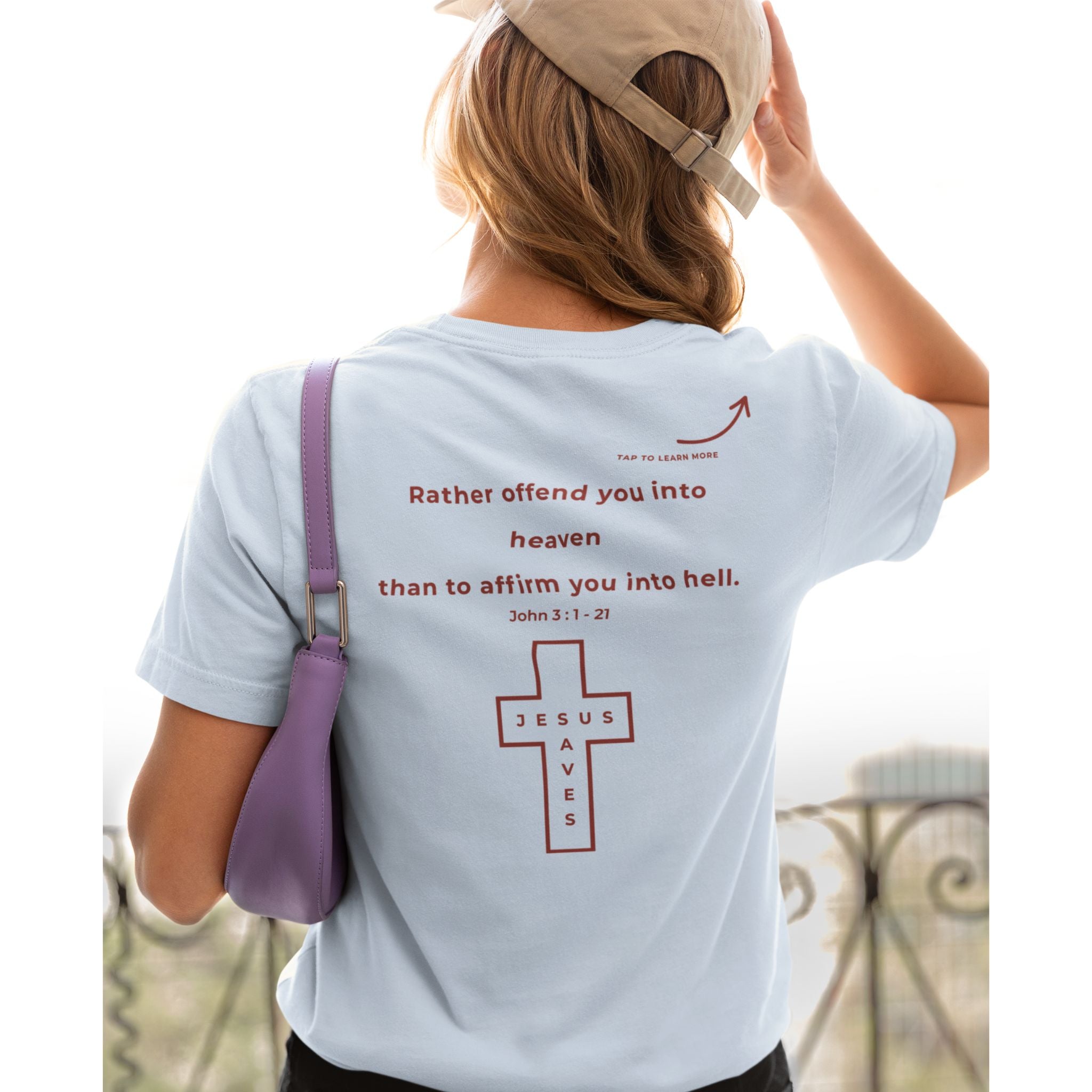 Back view of a woman wearing a light blue Christian T-shirt with a red “Rather offend you into heaven than affirm you into hell” message and Jesus Saves cross.